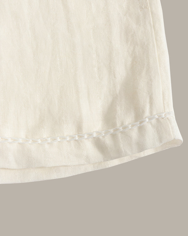 Close-up of a white fabric edge with a subtle pattern on a gray background