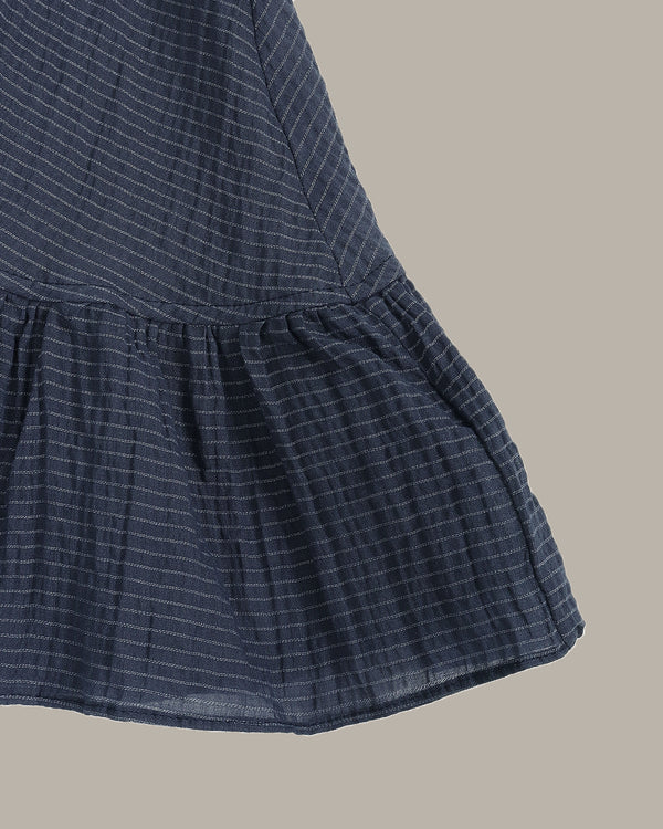 Navy blue ruffle top on a beige background