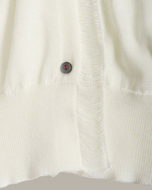 Close-up of a textured white fabric with a button featuring a red gemstone.