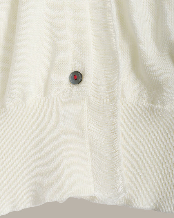 Close-up of a textured white fabric with a button featuring a red gemstone.