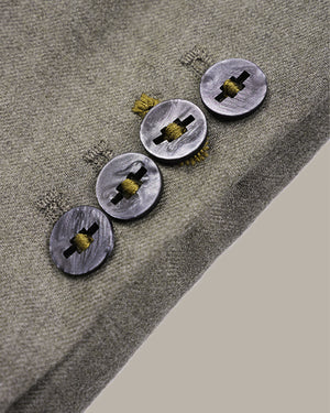 Close-up of a textured gray fabric surface with four round metallic buttons arranged diagonally, each featuring a black cross-shaped center and a small yellow loop detail.