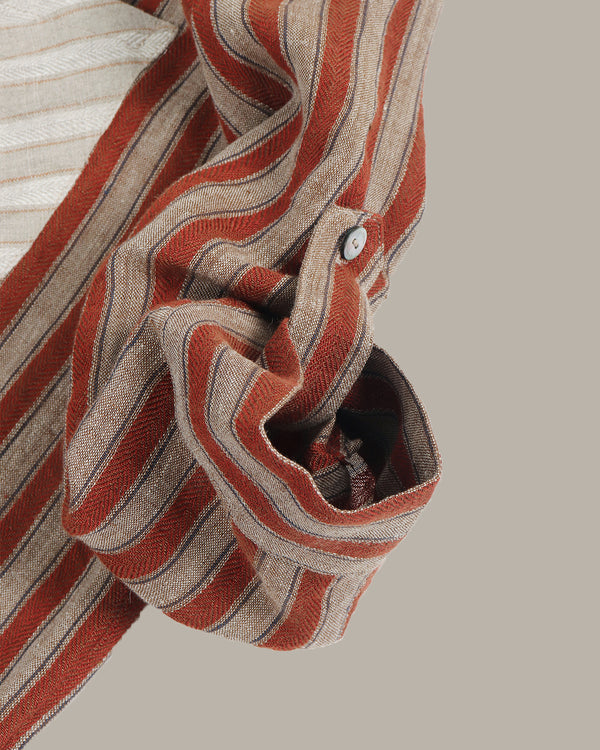 Close-up of a striped shirt's rolled up collar with red and beige colors on a neutral background