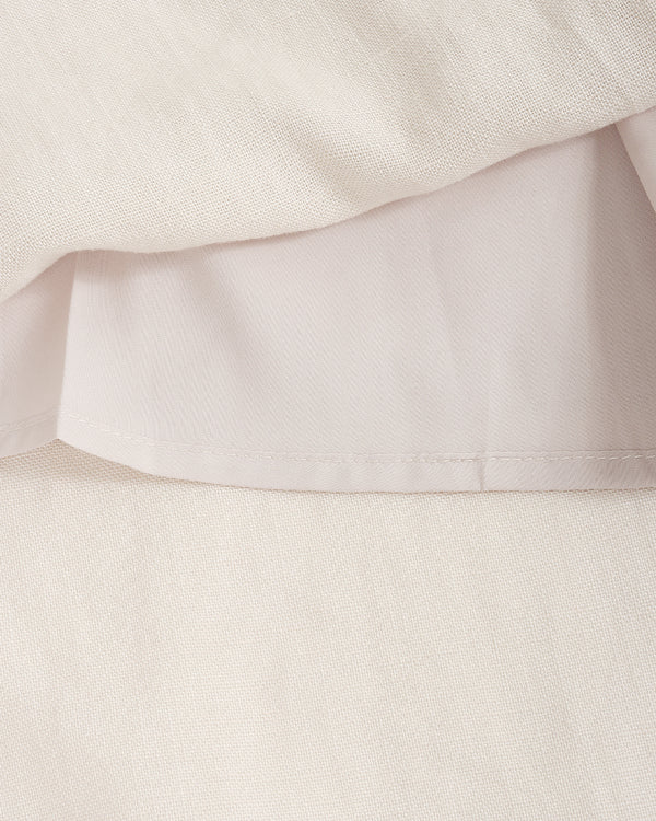 Close-up of a light cream or off-white fabric with a soft draped fold and visible woven texture.
