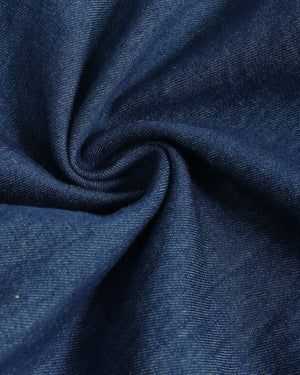 A close-up of dark blue denim fabric swirled in a spiral pattern, showing the detailed twill texture.