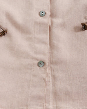 Close-up of a beige shirt with buttons and metal hardware