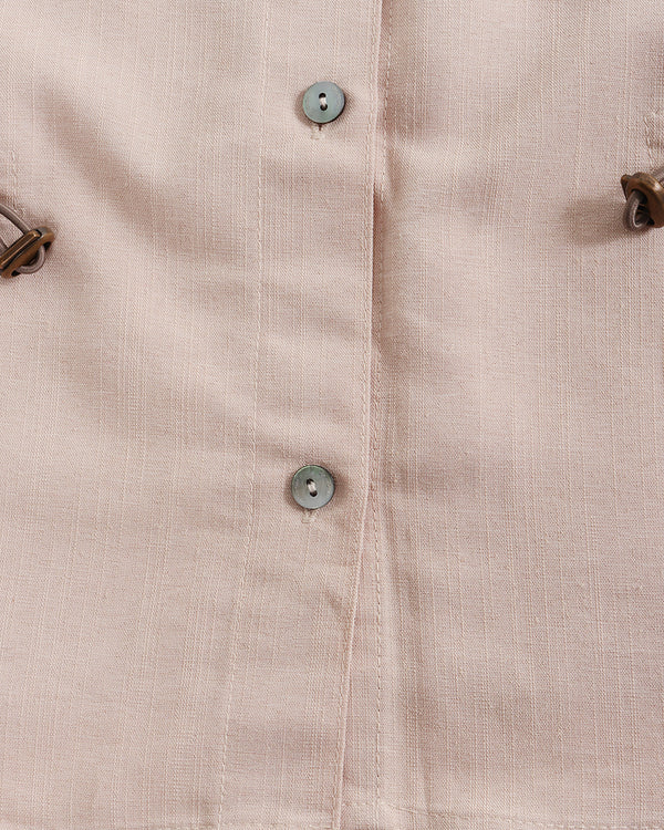 Close-up of a beige shirt with buttons and metal hardware