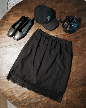 Black skirt, cap, and shoes on a wooden table