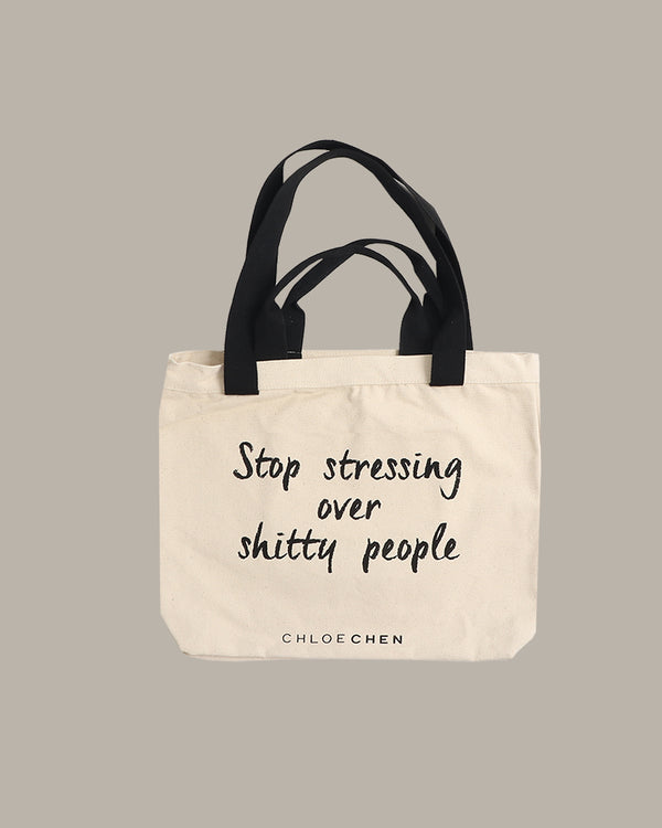 Tote bag with text 'Stop stressing over shitty people' by Chloe Chen on a beige background